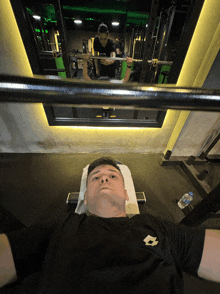a man in a black shirt with the letter l on it is lifting a barbell in a gym