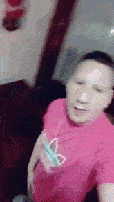 a man wearing a pink shirt with a butterfly on it is holding a toothbrush in his pocket .
