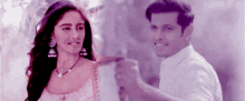 a man and a woman are standing next to each other holding hands and smiling .