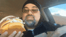 a man with a beard and glasses is holding a hamburger in his hand