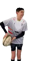 a young man holding a rugby ball and wearing a shirt that says ' mbc ' on it
