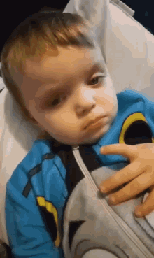 a little boy wearing a blue batman pajama is laying on a bed