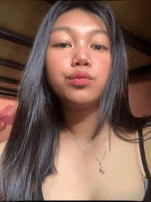 a woman wearing a black tank top and a silver necklace with a star on it