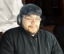 a man wearing glasses and headphones has a viggle ai logo on the bottom right of his face