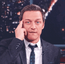 a man in a suit and tie is touching his head