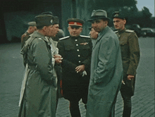 a group of men in military uniforms and hats are standing around talking