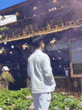 a man is standing in front of a house with flowers in front of it