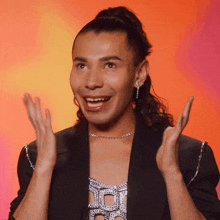 a man with a ponytail is wearing a black jacket and silver necklace