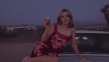 a woman in a pink dress sits on the hood of a white truck