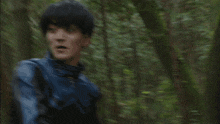 a man in a leather jacket is running through the woods