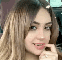 a close up of a woman 's face with her finger on her mouth
