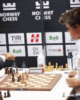 a man playing chess in front of a norway chess sign