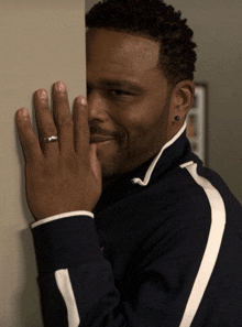 a man with a ring on his finger is peeking over a wall