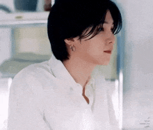 a close up of a young man wearing a white shirt and earrings .