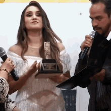a woman in a white dress holds a trophy that says ' premio ' on it