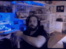 a man with a beard is sitting in front of a computer in a room with a fish tank in the background .