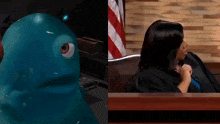 a woman in a judge 's robe sits next to a blue monster .