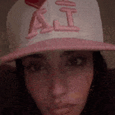 a woman wearing a pink and white hat with the letter ai on it