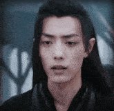 a man with long hair is wearing a black shirt and scarf