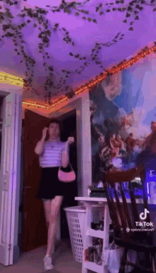 a girl is dancing in a room with a purple ceiling and a painting on the wall .