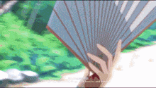 a person is holding a fan in their hand with chinese writing on the bottom