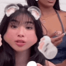 a close up of a woman wearing a cat ear headband and holding a bottle .