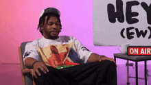 a man is sitting in front of a sign that says hey ( ew )
