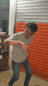a man in a white shirt is dancing in front of an orange garage door