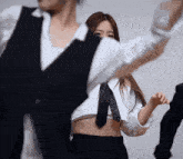 a woman in a crop top and tie is dancing with a man in a suit