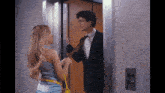 a man in a suit is talking to a woman in a blue dress