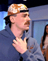 a man with a mustache wearing a hat and a hoodie that says ' california ' on it