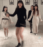 a woman in a black dress is dancing in a room with other girls