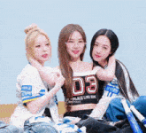 three girls are posing for a picture with one wearing a number 03 shirt