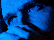 a close up of a man 's face with blue light behind it