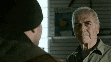 a man in a hat talks to an older man