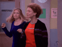 two women are dancing in a hallway in front of a sign that says " a " on it .