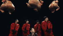 a group of men in red jumpsuits are looking up at chickens in the air