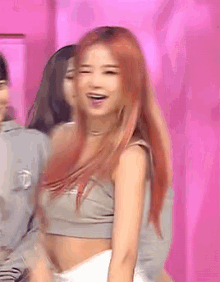 a woman with red hair is wearing a grey crop top and white skirt