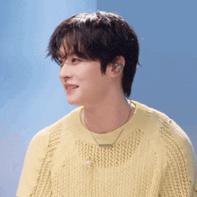 a man wearing a yellow sweater and a necklace
