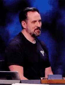 a man with a beard wears a black shirt with a bull on the front