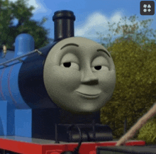 a close up of a thomas the tank engine 's face with trees in the background