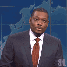 a man in a suit and tie is standing in front of a snl sign