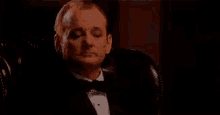 a man in a tuxedo is holding a glass of whiskey and saying make it suntory time .