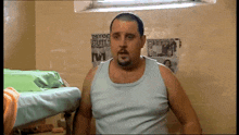 a man in a blue tank top is standing in front of a wall with a poster that says they 're not guilty