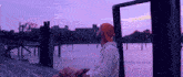 a man in an orange hat sits on a dock looking at the water
