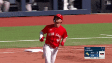 a baseball player wearing a red blue jays jersey is running on the field