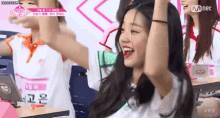 a group of girls are sitting in a classroom with their hands in the air