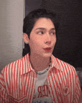 a young man wearing a red and white striped shirt with a necklace and a t-shirt that says " web " on it