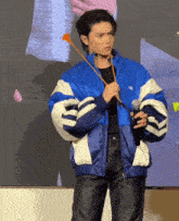 a man in a blue jacket holds a microphone