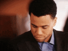a man in a suit and a blue shirt is looking down